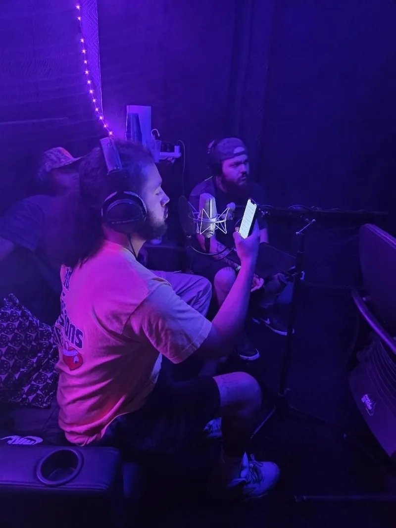 Headphones on over the laptop, the Purple Sound neon lighting the table